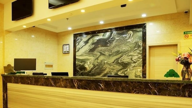 A reception desk with a marble top, a large abstract painting, a television, and a vase with flowers. - GreenTree Inn Changzhou Henlin Town Zhongtian Express Hotel (Changzhou)