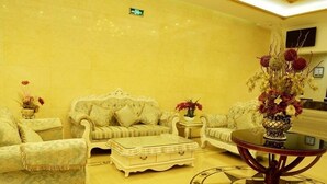 A yellow-walled room with a sofa set, a coffee table, and a decorative vase with flowers. - GreenTree Inn Changzhou Henlin Town Zhongtian Express Hotel (Changzhou)