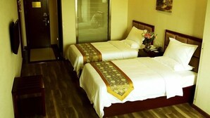A hotel room with two beds, a small table, a chair, a door, and a painting on the wall. - GreenTree Inn Changzhou Henlin Town Zhongtian Express Hotel (Changzhou)