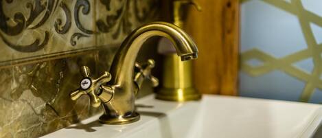 A bathroom with a gold faucet, a white sink, and decorative tiles.
