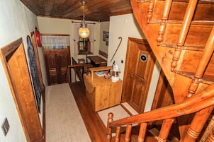 Una escalera de madera con barandilla de madera y una puerta de madera con un ventanal redondo.