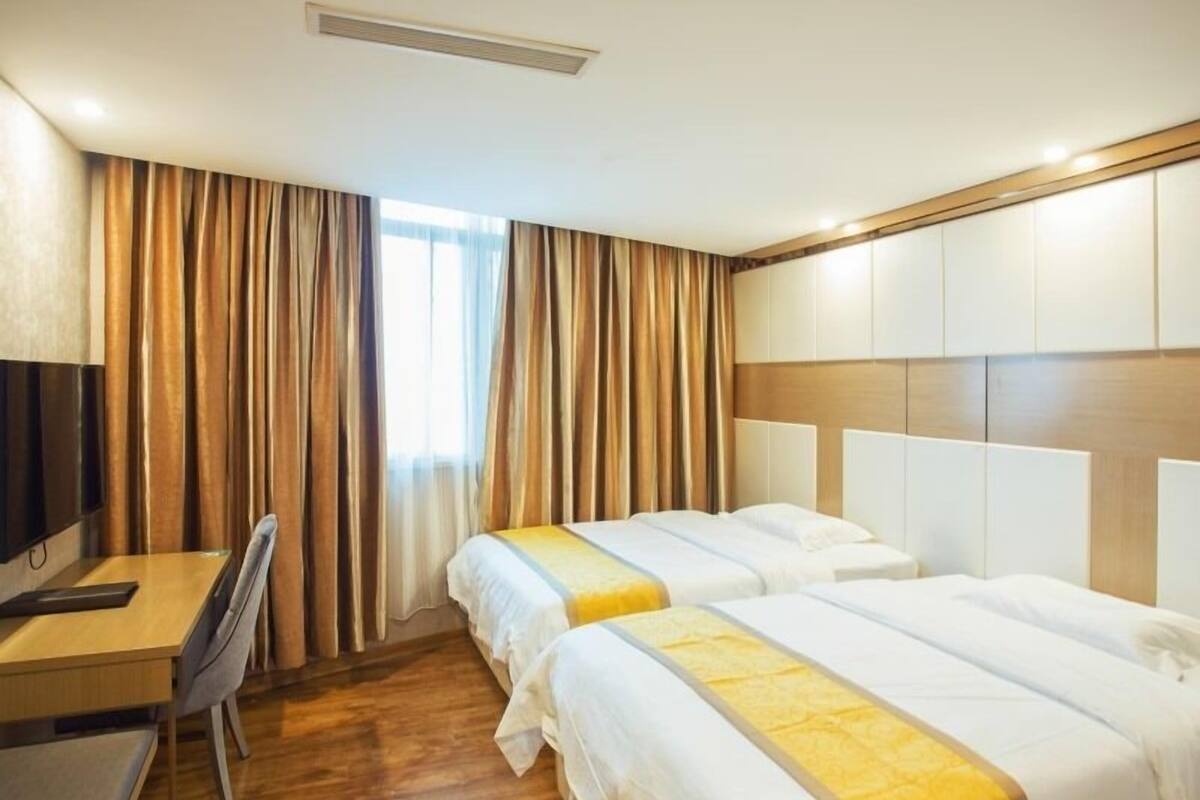 Una habitación de hotel con dos camas, un escritorio y televisión.