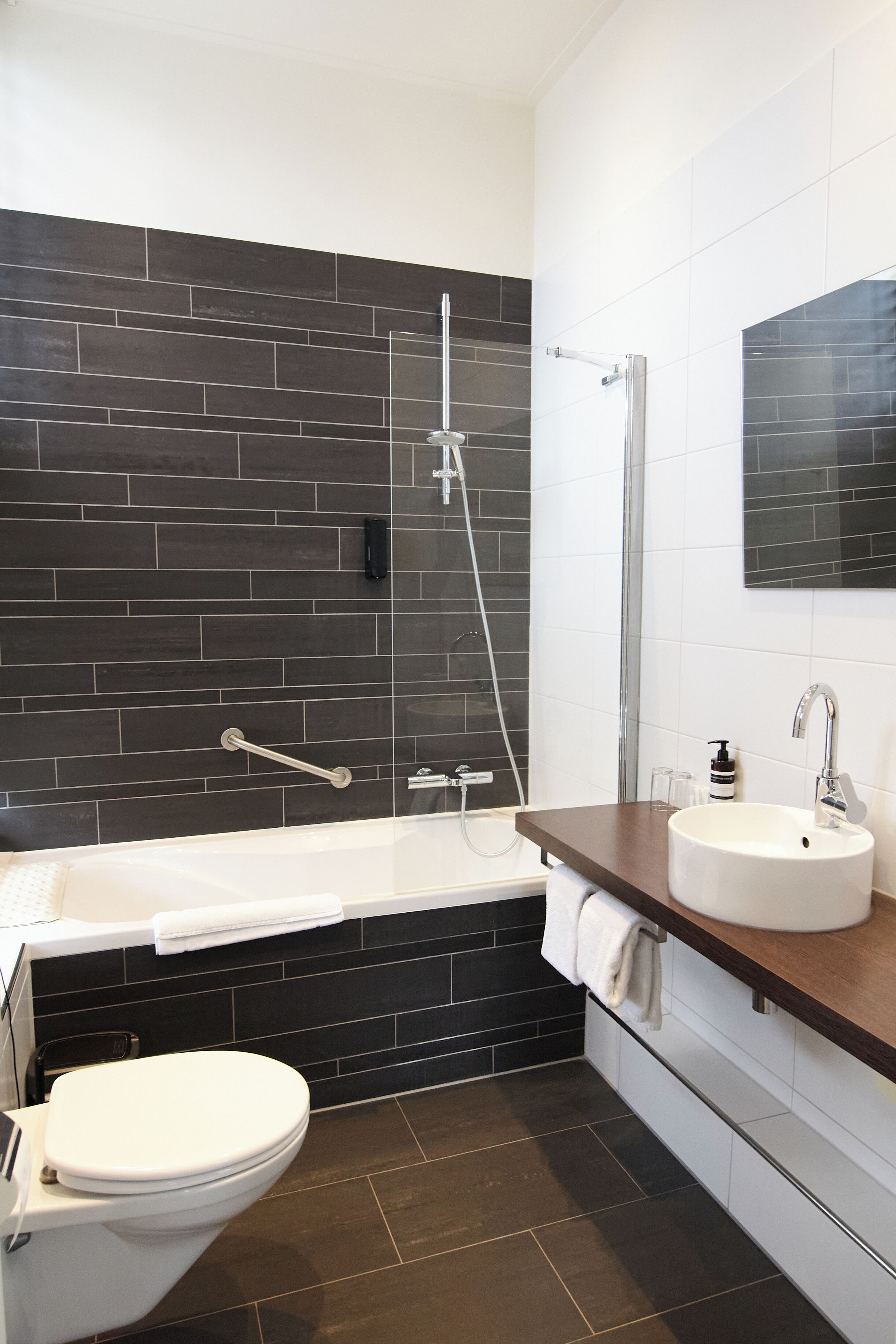 A modern bathroom with a bathtub, toilet, and a shower area.
