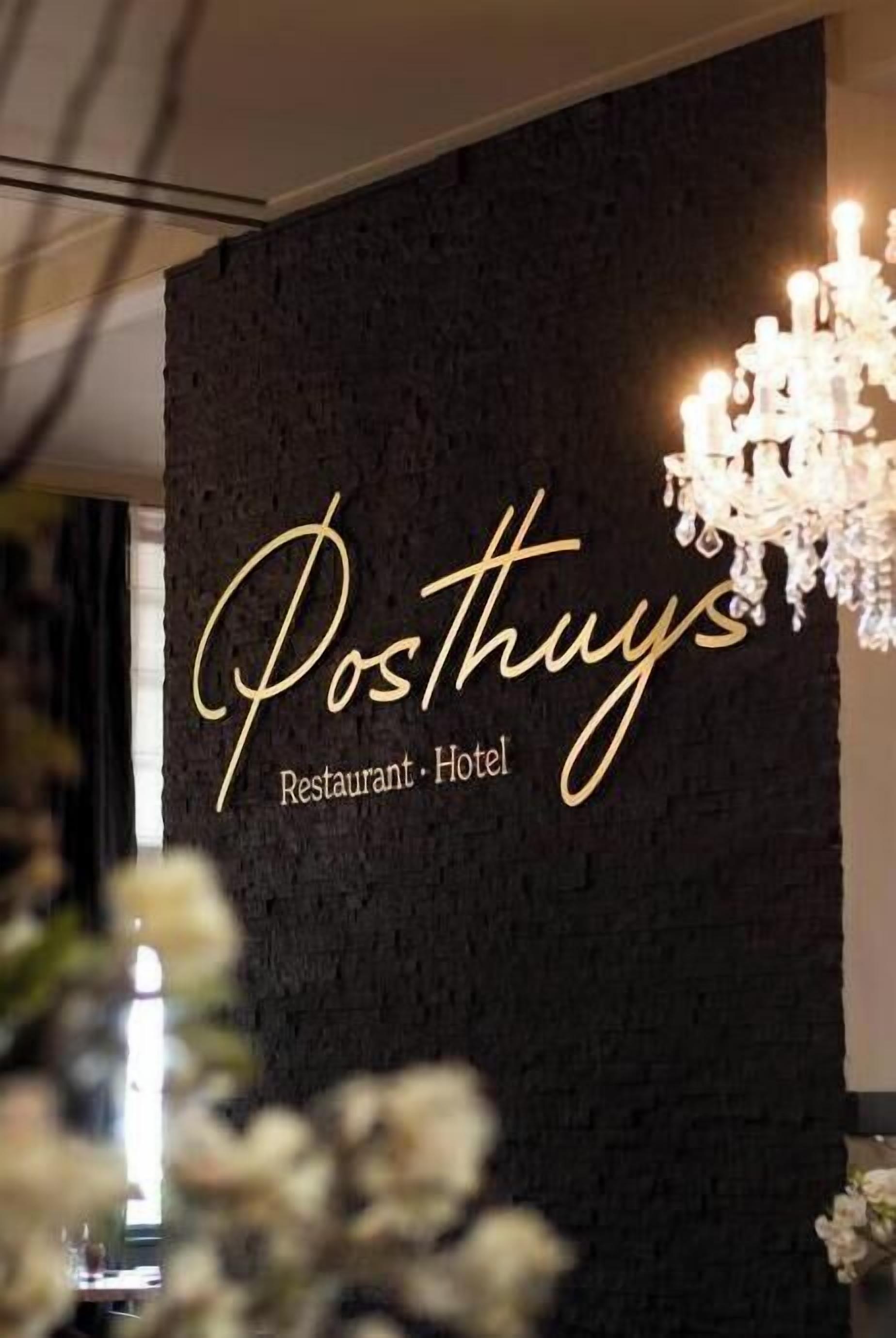Een muur met de naam 'Posthuy's Restaurant - Hotel' in sierlijke letters.