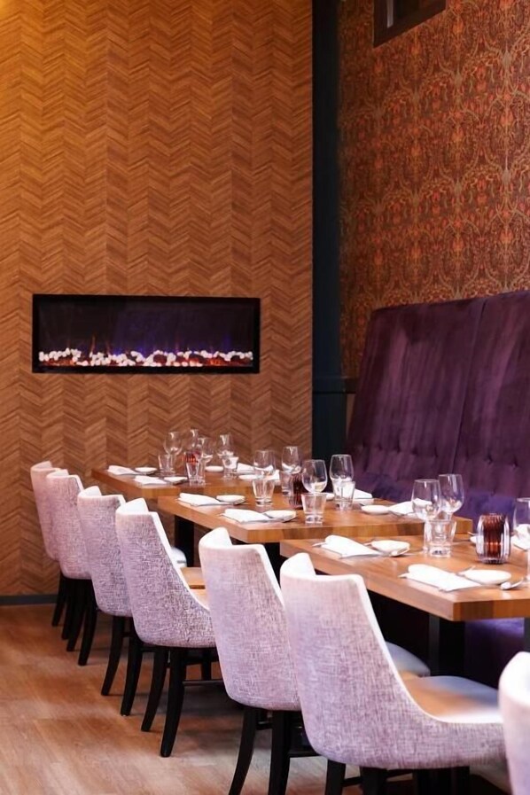 Comedor con una mesa larga dispuesta para varios comensales, sillas y una chimenea.