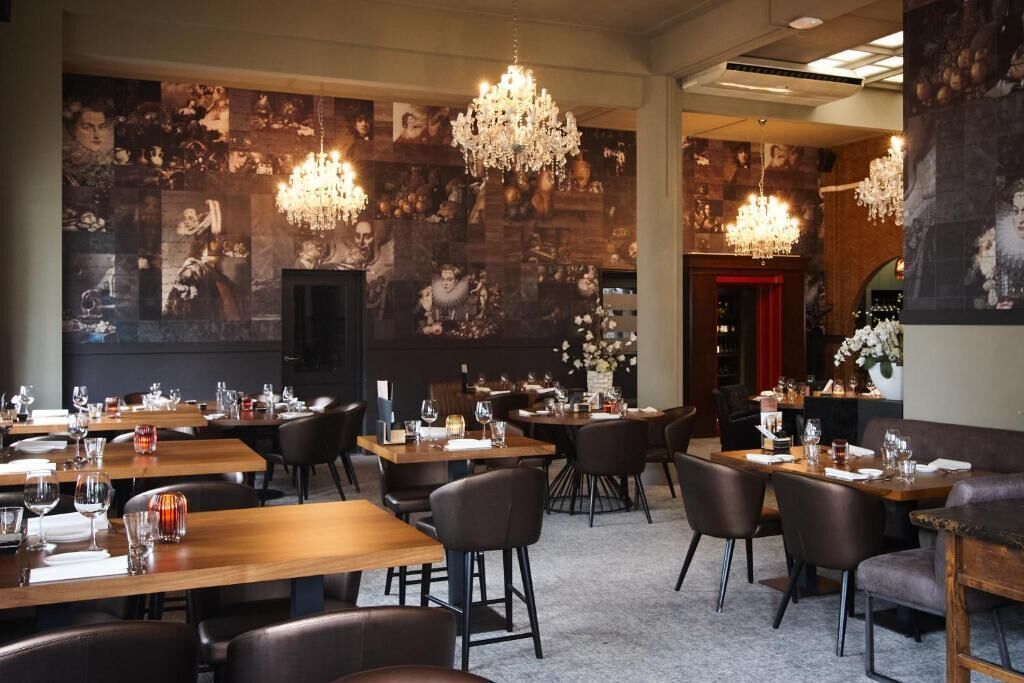 Un interior de restaurante con varias mesas, sillas y candelabros.