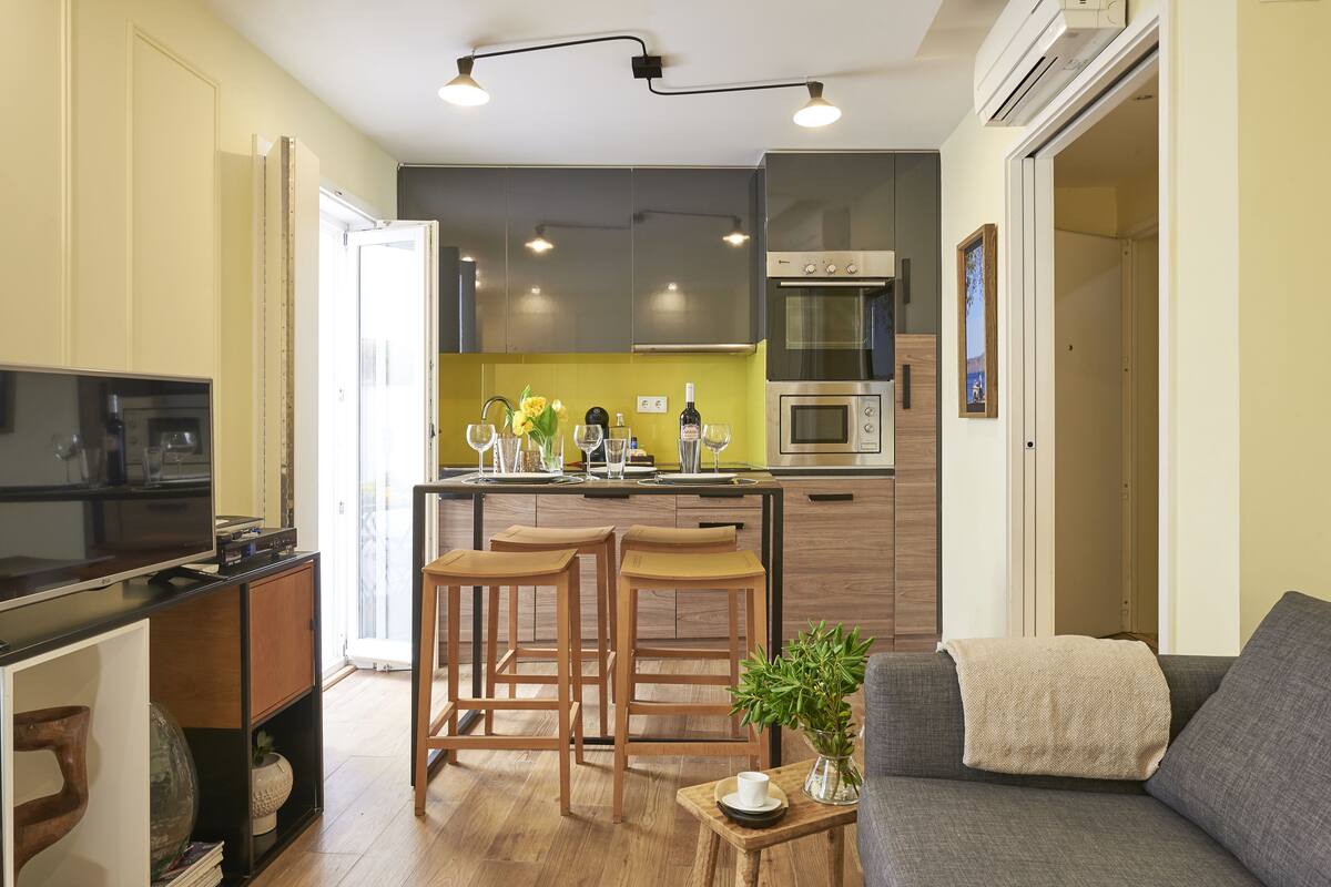 A modern kitchen with a central island, bar stools, and a built-in oven.