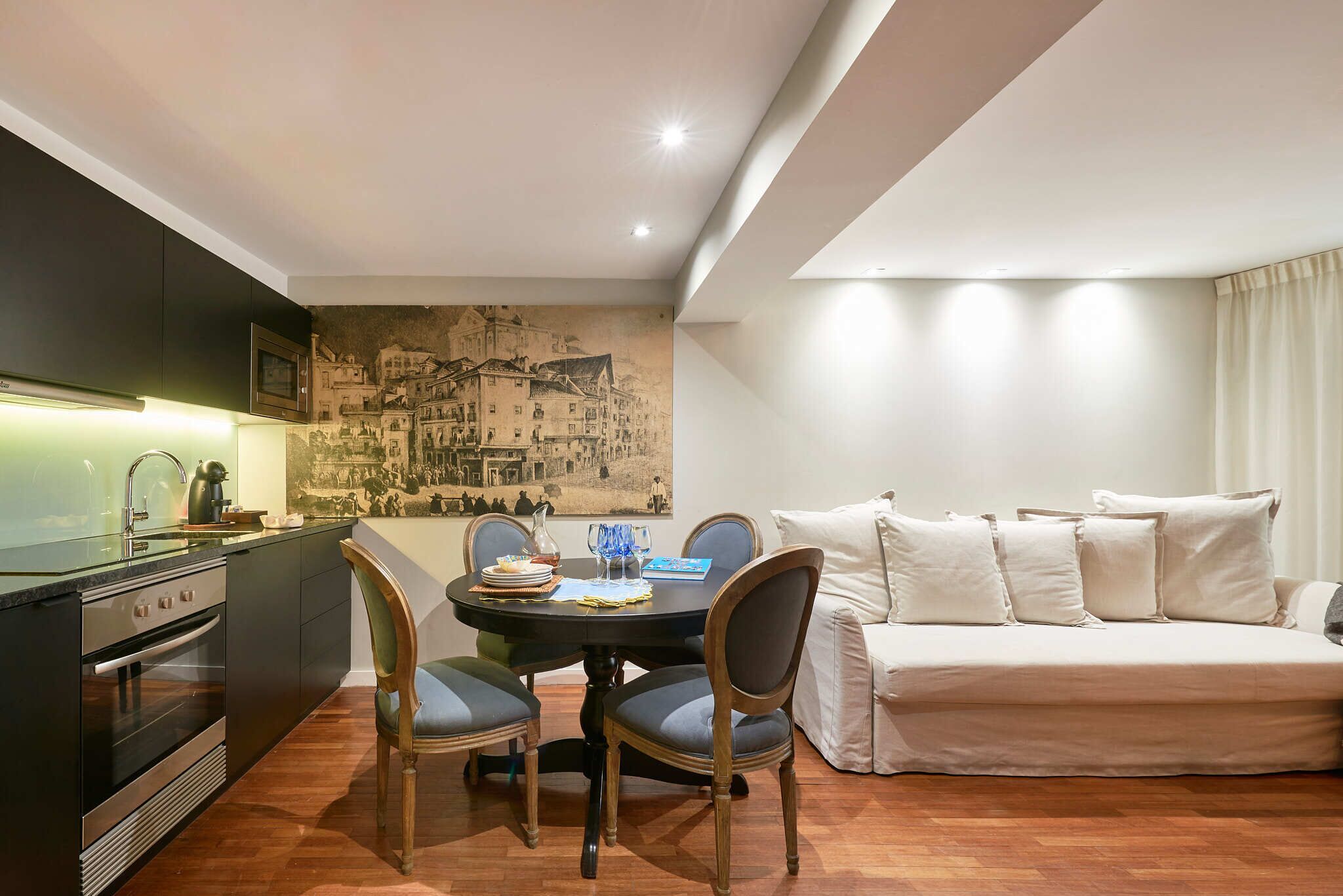 Een ruimtelijke woonkamer met kitchenette, eethoek en een bank.