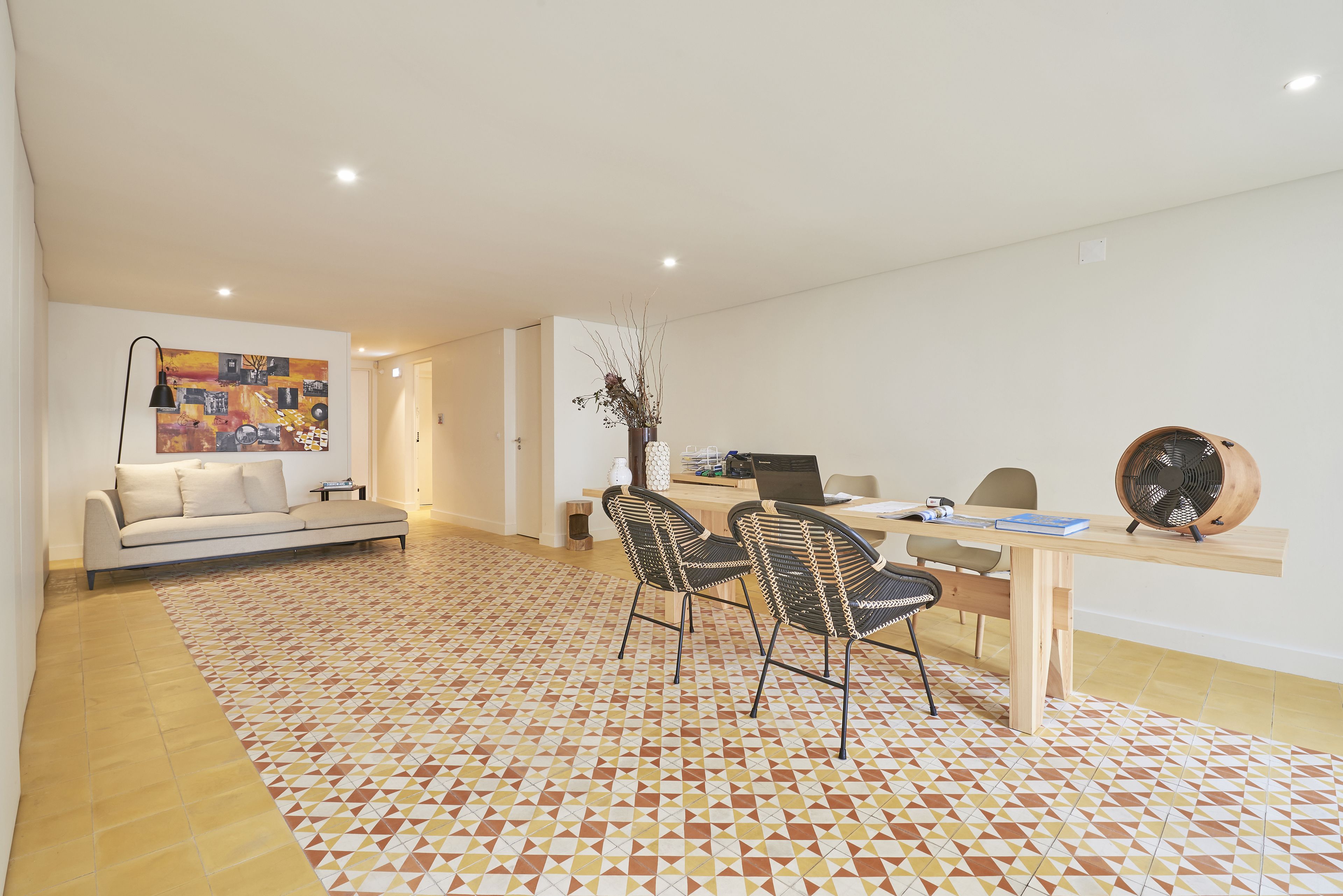 Un salon moderne comprenant un canapé, deux fauteuils, une table à manger et un ordinateur portable.