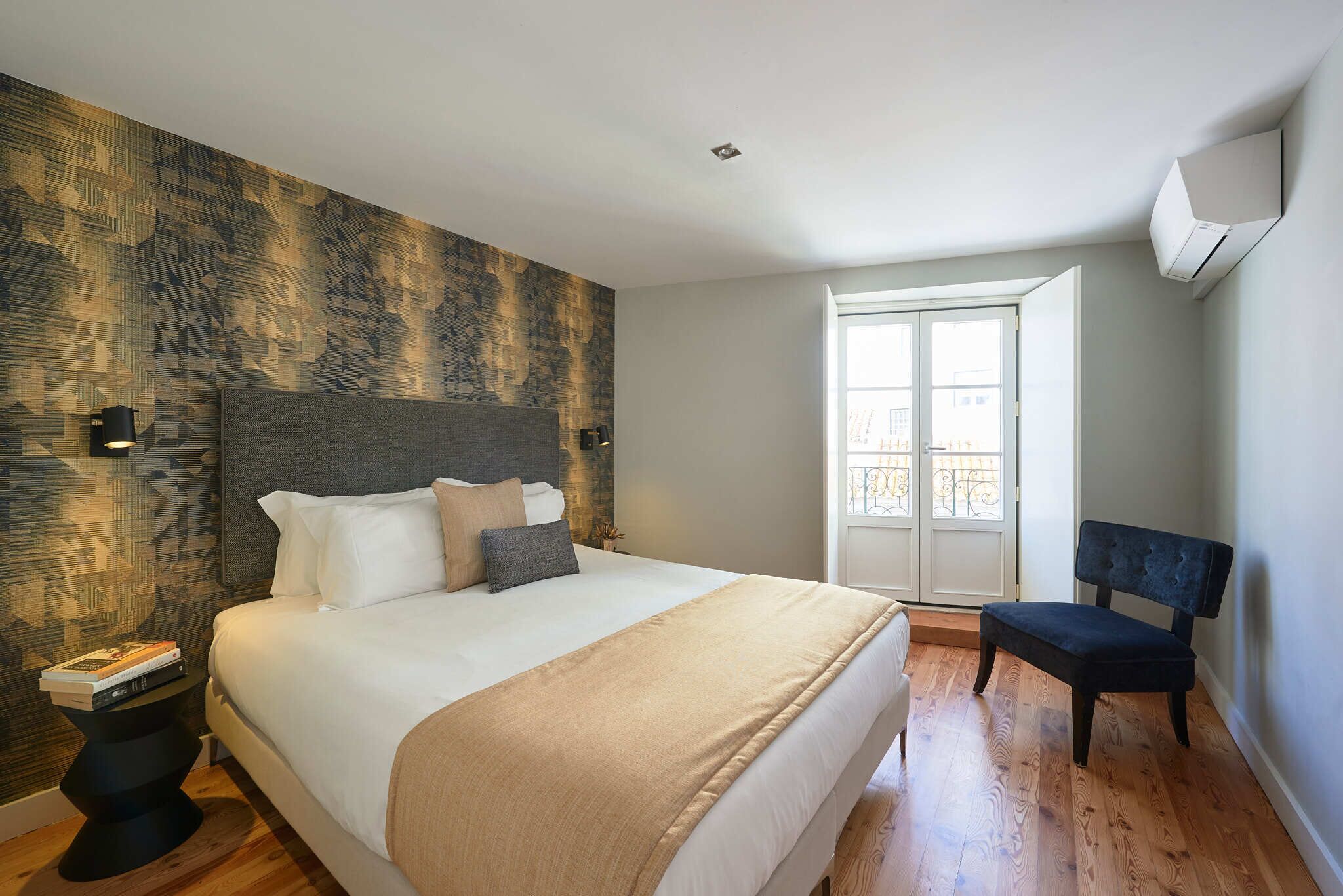 Een moderne slaapkamer met een groot bed, een nachtkastje, een stoel, een raam en een airconditioning.