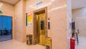 A lobby with a marble floor, an elevator, and a small trash bin. - GreenTree Inn Nantong Chongchuan District Middle Changjiang Road Express Hotel (Nantong)