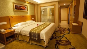 A hotel room with a large bed, a bedside table, a mirror, and a carpet with a floral pattern. - GreenTree Inn ZhuHai Jinwan District Zhuhai Airport Jilin University Hotel (Zhuhai)