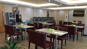 A hotel dining area with tables and chairs, a water dispenser, and a television on the wall. - GreenTree Inn ZhuHai Jinwan District Zhuhai Airport Jilin University Hotel (Zhuhai)