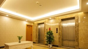 A lobby with marble flooring, a white bench, two elevators, and a potted plant. - GreenTree Inn ZhuHai Jinwan District Zhuhai Airport Jilin University Hotel (Zhuhai)