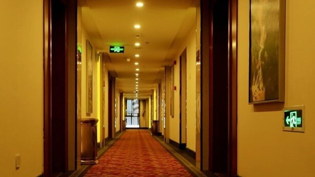 A hotel hallway with a red carpet, doors on both sides, and exit signs. - GreenTree Inn HeFei Heyu Road Dayun City Express Hotel (Hefei)