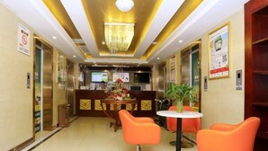 A hotel lobby with a reception desk, a chandelier, orange chairs, and a small table with a plant. - GreenTree Inn HeFei Heyu Road Dayun City Express Hotel (Hefei)