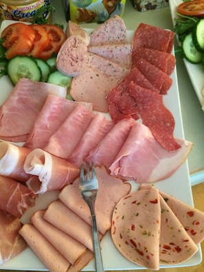 Variedad de embutidos y quesos sobre un plato blanco.