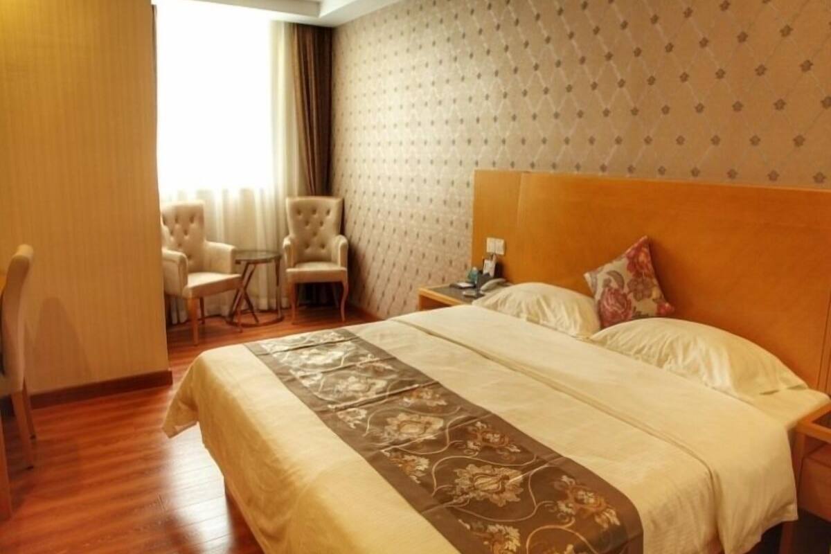 A hotel room with a large bed, a nightstand, a chair, and a small table.