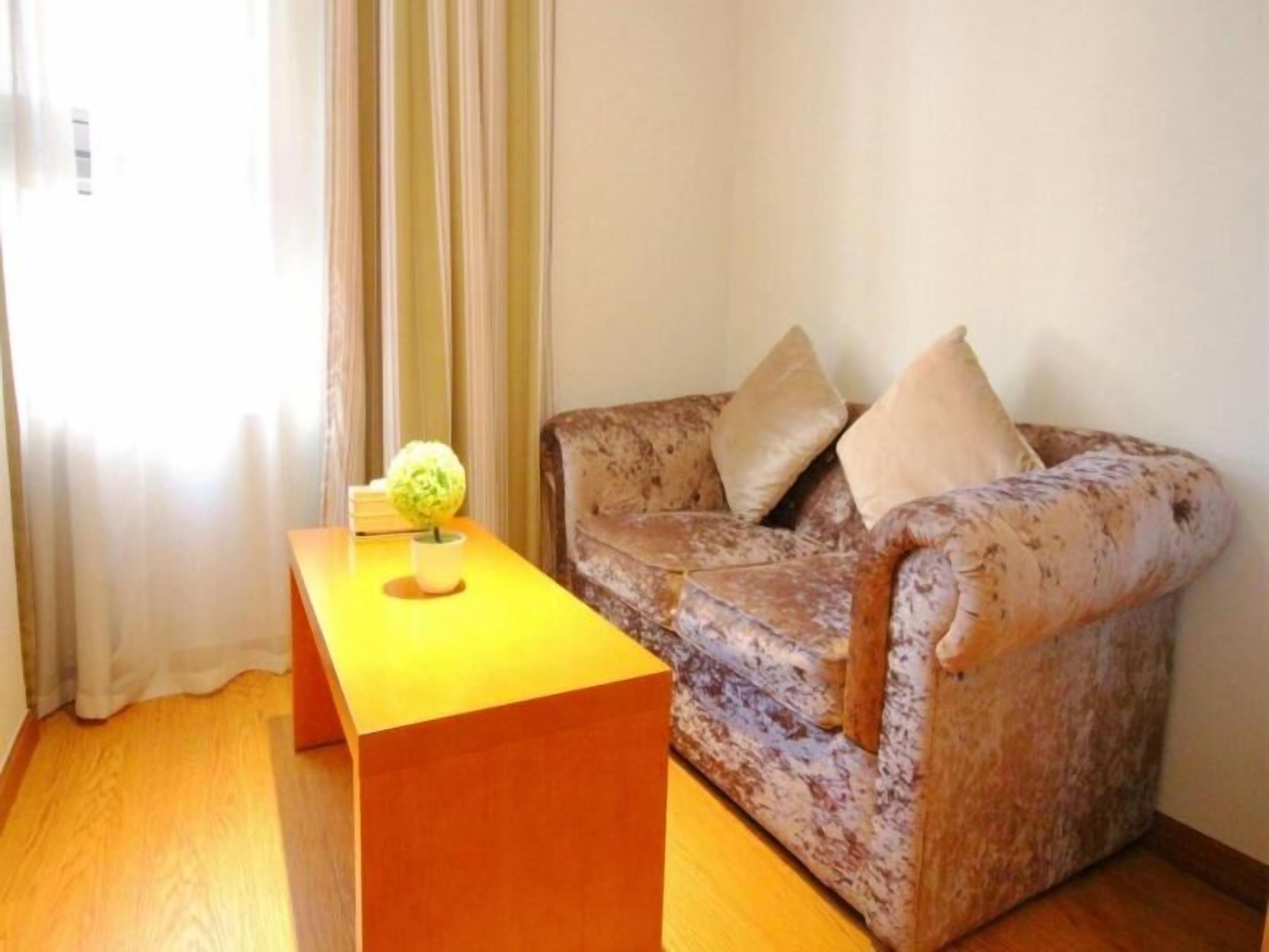 A living room with a patterned sofa, a wooden coffee table, and a small potted plant.