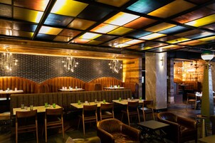 A restaurant with booths and tables, a brick wall, and a colorful ceiling.