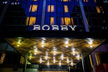 Welcome to Bobby, a stylish building with a modern design featuring a unique entrance with a wooden ceiling and embedded lighting. at Bobby Hotel