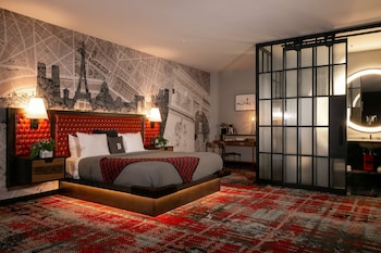 Experience a unique blend of art and comfort in this stylish room, featuring a large bed, a cityscape mural, and a spacious workspace. at Bobby Hotel