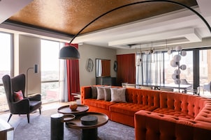 Uma sala de estar moderna com um sofá grande laranja, uma poltrona preta e uma mesa de centro redonda.