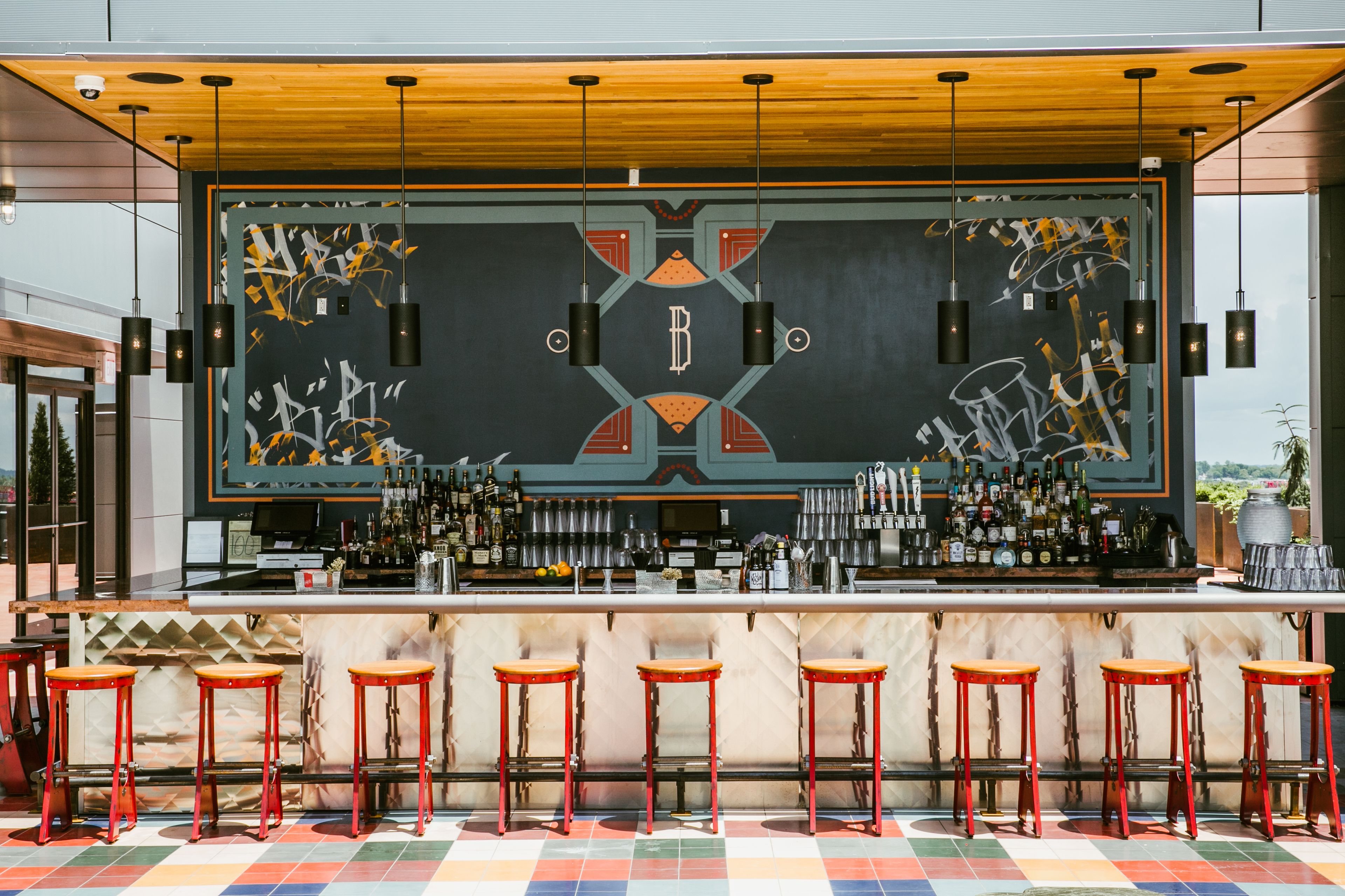 A bar area with a counter, stools, and a decorative wall.