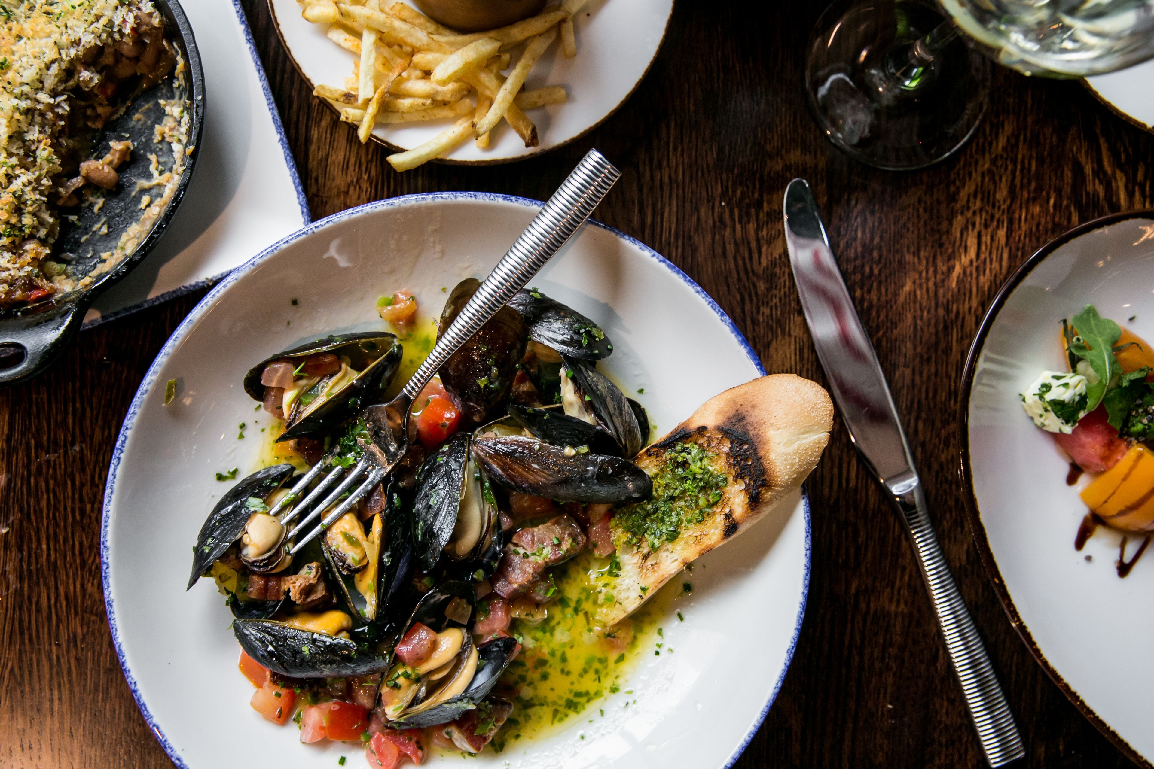 A seafood dish with mussels, tomatoes, and herbs on a plate.