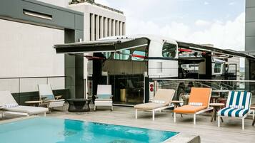 A rooftop pool area with lounge chairs and a cabana.