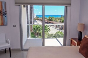 Une chambre d’hôtel dotée d’une grande porte-fenêtre coulissante donnant sur un balcon avec vue sur l’océan et un espace de stationnement.