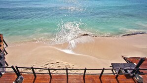 Een strand met een houten terras en ligstoelen richting de zee.