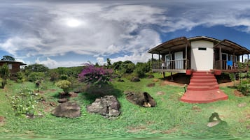 A house with a porch, surrounded by greenery and rocks.