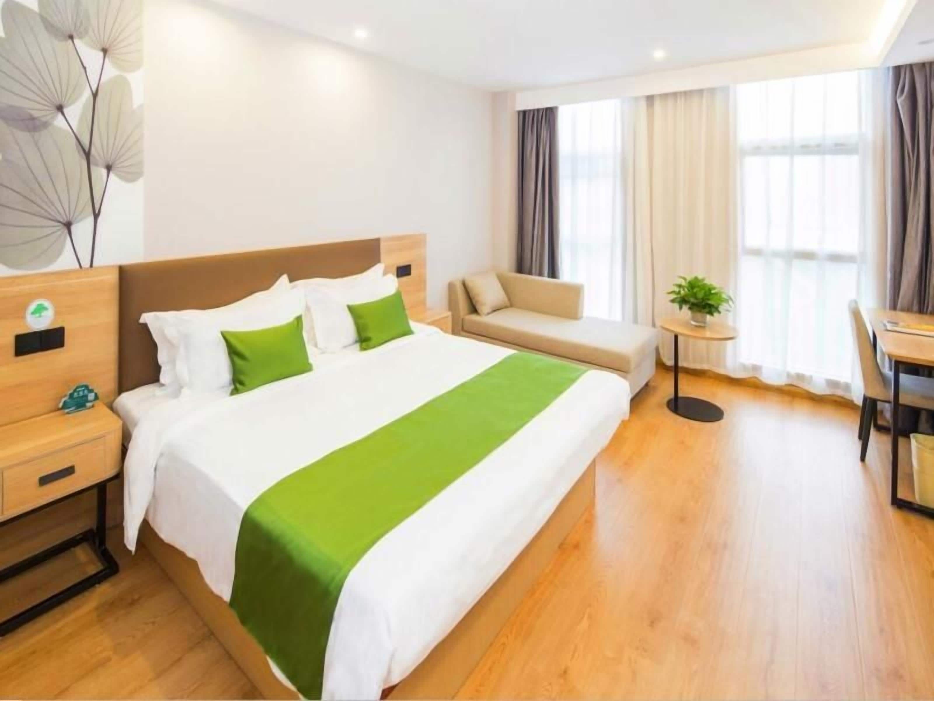 Ein Hotelzimmer mit einem großen Bett, einer Sitzecke, einem Schreibtisch und einem kleinen Tisch mit einer Pflanze.