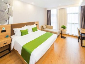 A hotel room with a large bed, a sofa, a desk, and a small table with a plant. - GreenTree Inn Tianjin Xiqing Development Zone Renrenle Square Express Hotel (Tianjin)
