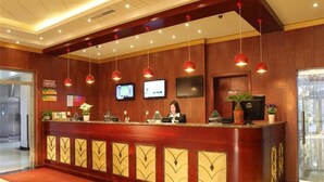 A hotel reception area with a wooden reception desk, multiple pendant lights, and a flat-screen TV mounted on the wall. - GreenTree Inn Tianjin Xiqing Development Zone Renrenle Square Express Hotel (Tianjin)
