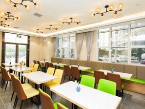 A modern dining area with multiple tables and chairs, large windows with curtains, and decorative ceiling lights. - GreenTree Inn Tianjin Xiqing Development Zone Renrenle Square Express Hotel (Tianjin)
