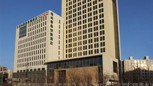 A multi-story hotel with a grid-like facade, featuring numerous windows and a prominent signage on the left side. - GreenTree Inn Tianjin Xiqing Development Zone Renrenle Square Express Hotel (Tianjin)