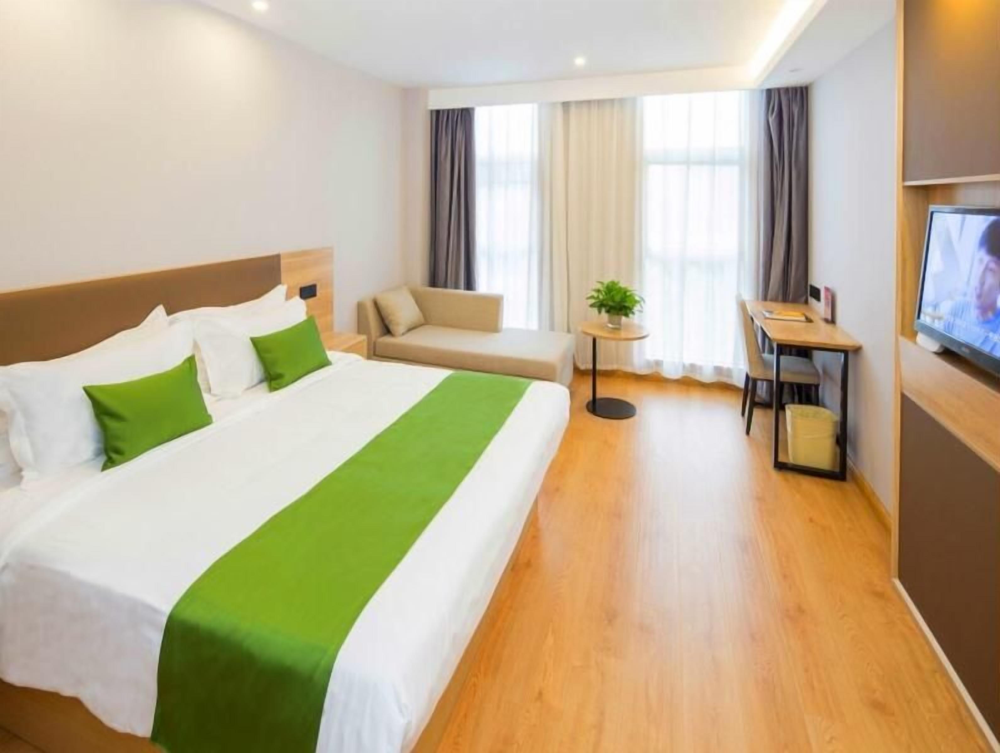 Une chambre d’hôtel avec un grand lit, un canapé, un bureau et une télévision.