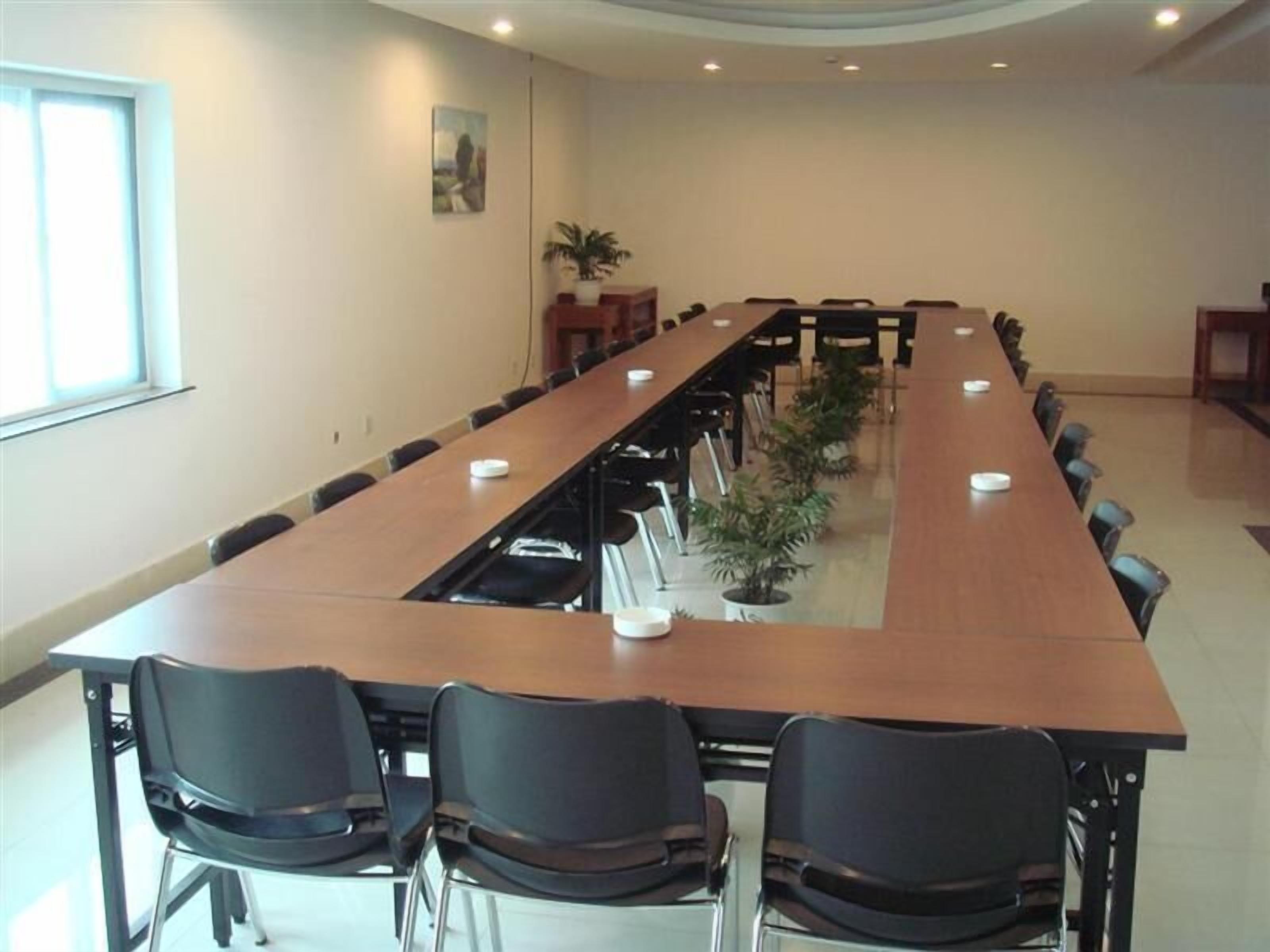 A conference room with a long table, black chairs, and a potted plant.