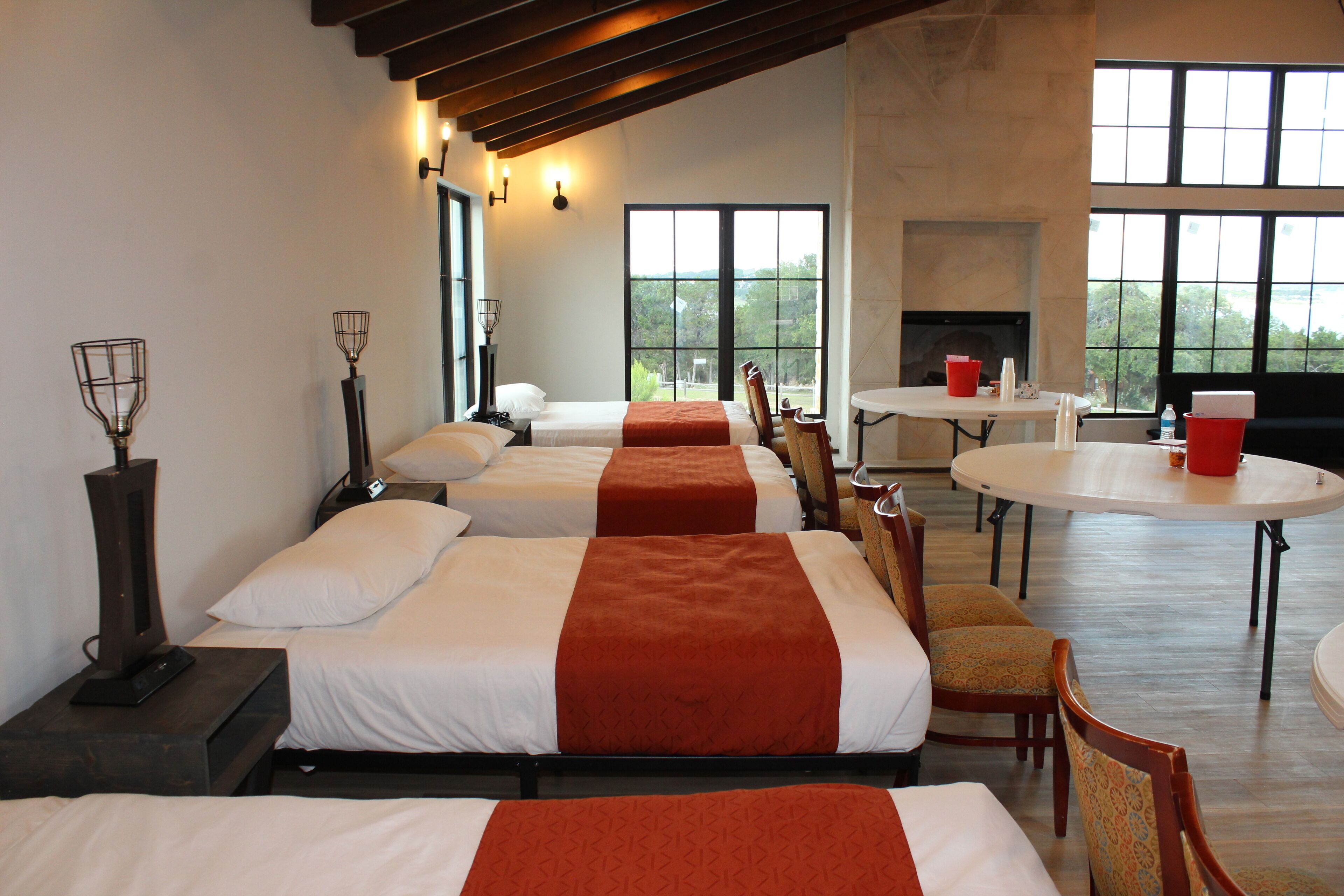 A hotel room with three beds, a dining table, and a fireplace.
