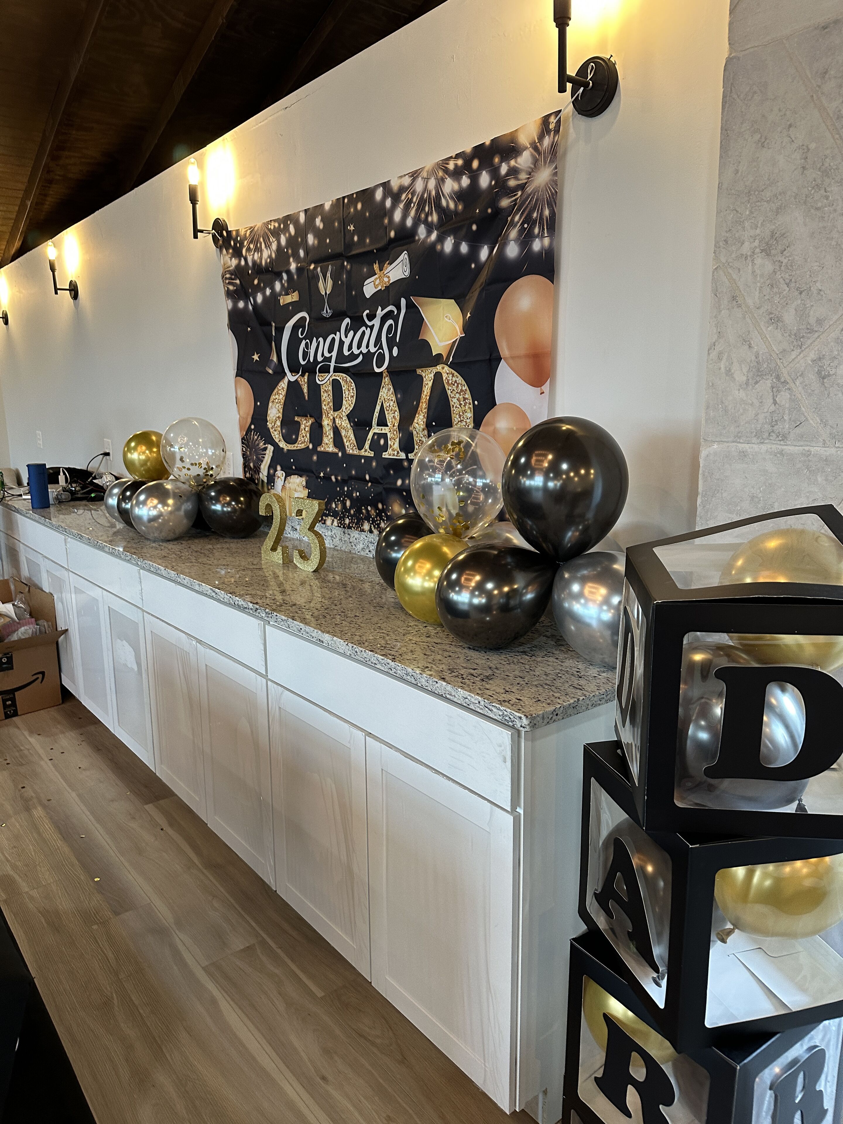Una encimera de cocina con un fondo alusivo a la graduación, globos y un cartel que dice '¡Felicidades, GRAD!'.