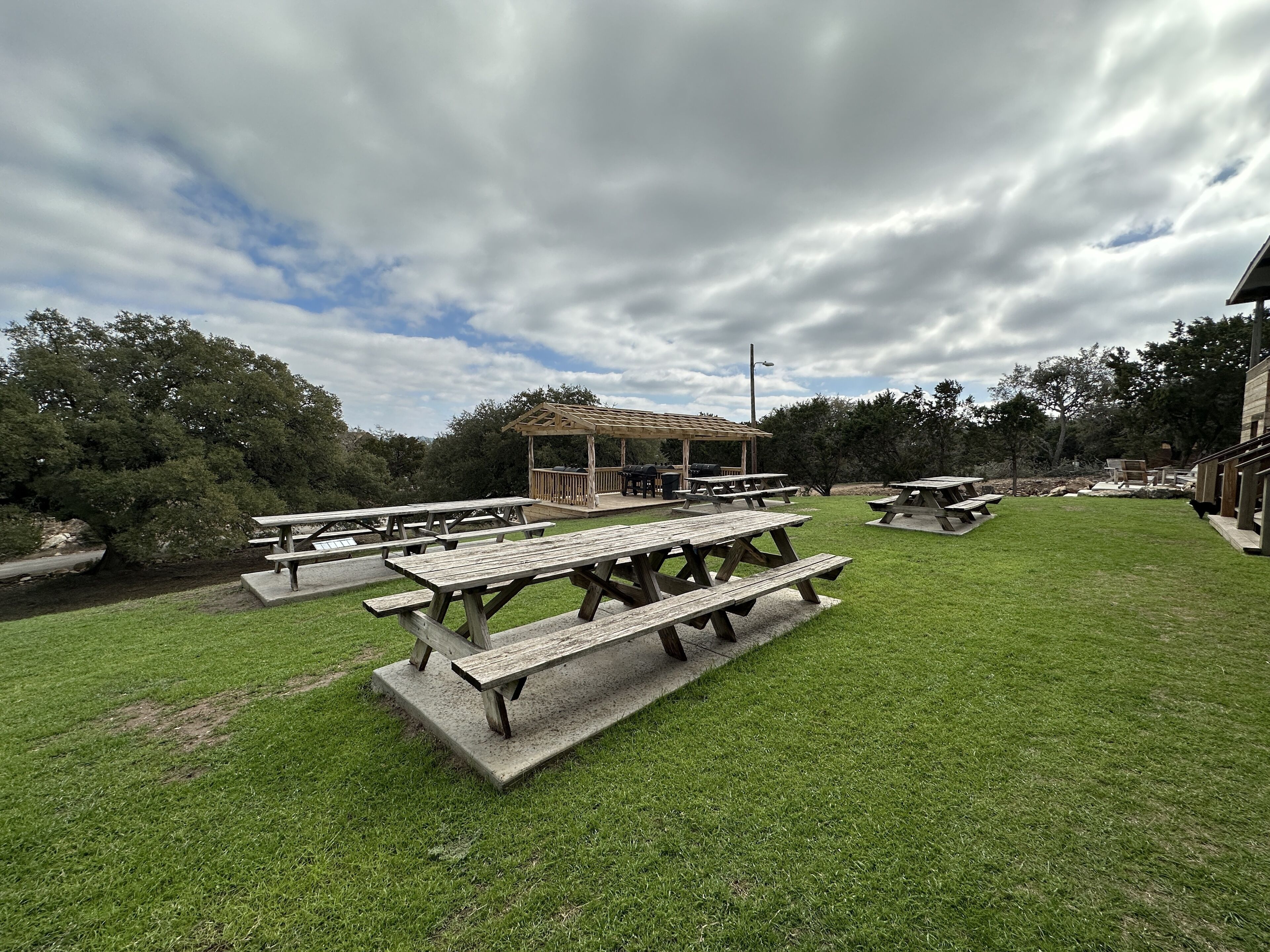 Ein Picknickplatz mit mehreren Holztischen und einem überdachten Pavillon.