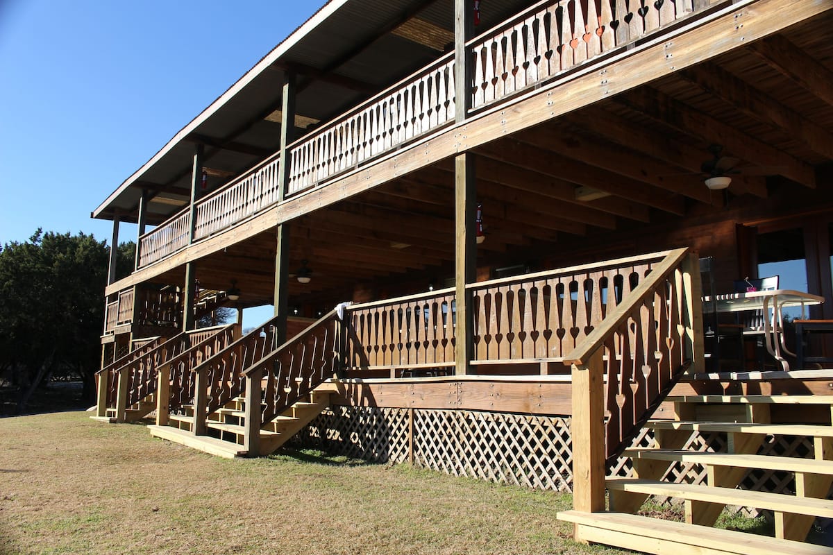 A wooden deck with a staircase leading to a balcony.