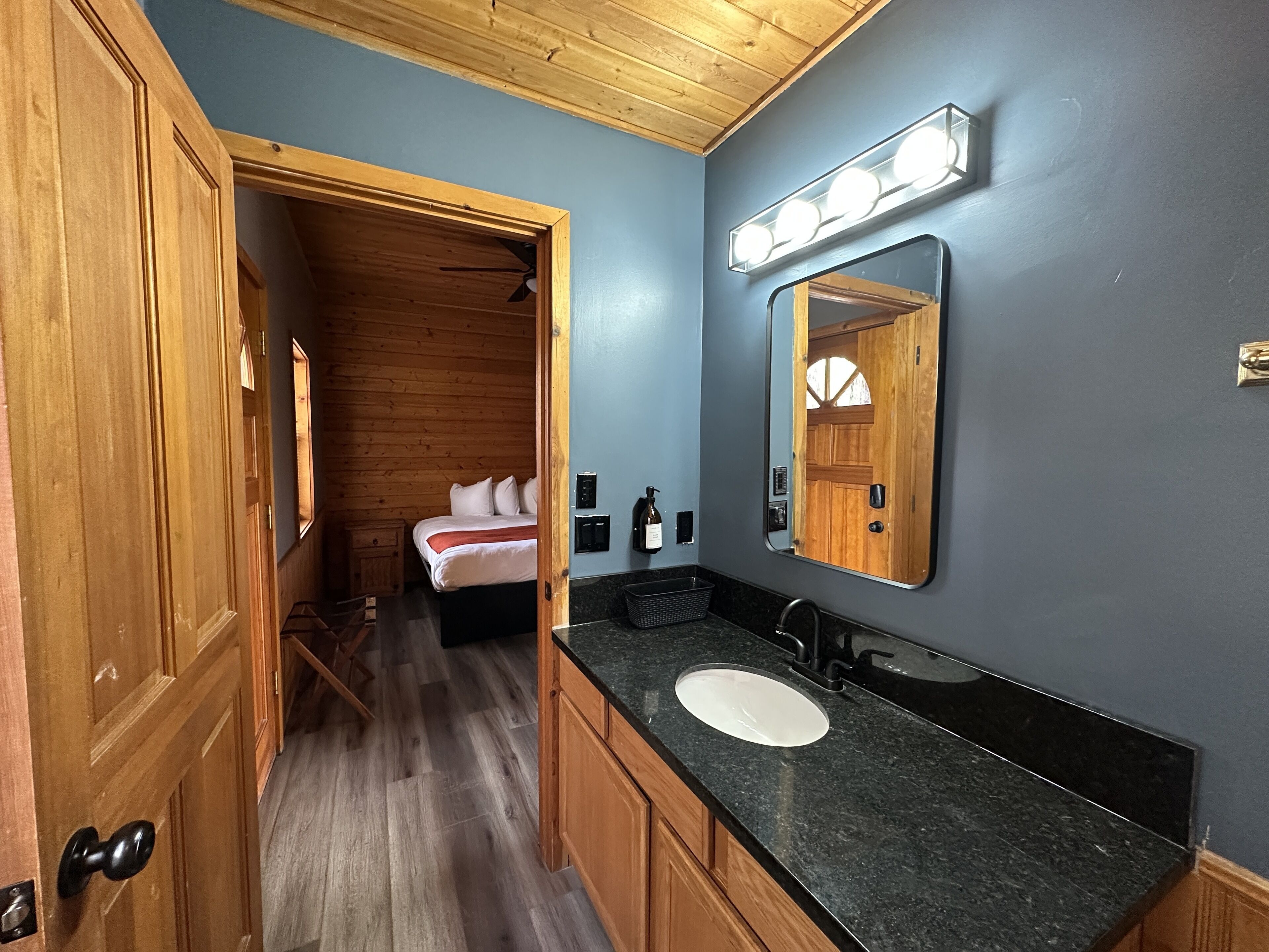 A compact, modern bathroom with a wooden vanity, a large mirror, and a built-in sink.