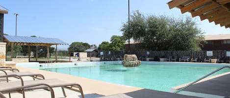 A swimming pool with lounge chairs and a covered area.