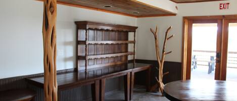 A wooden bench, a bookshelf, and a round table in a room with a wooden ceiling and an exit sign.
