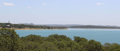 Un paisaje costero con una vista despejada del mar, una playa de arena y un área boscosa en primer plano.