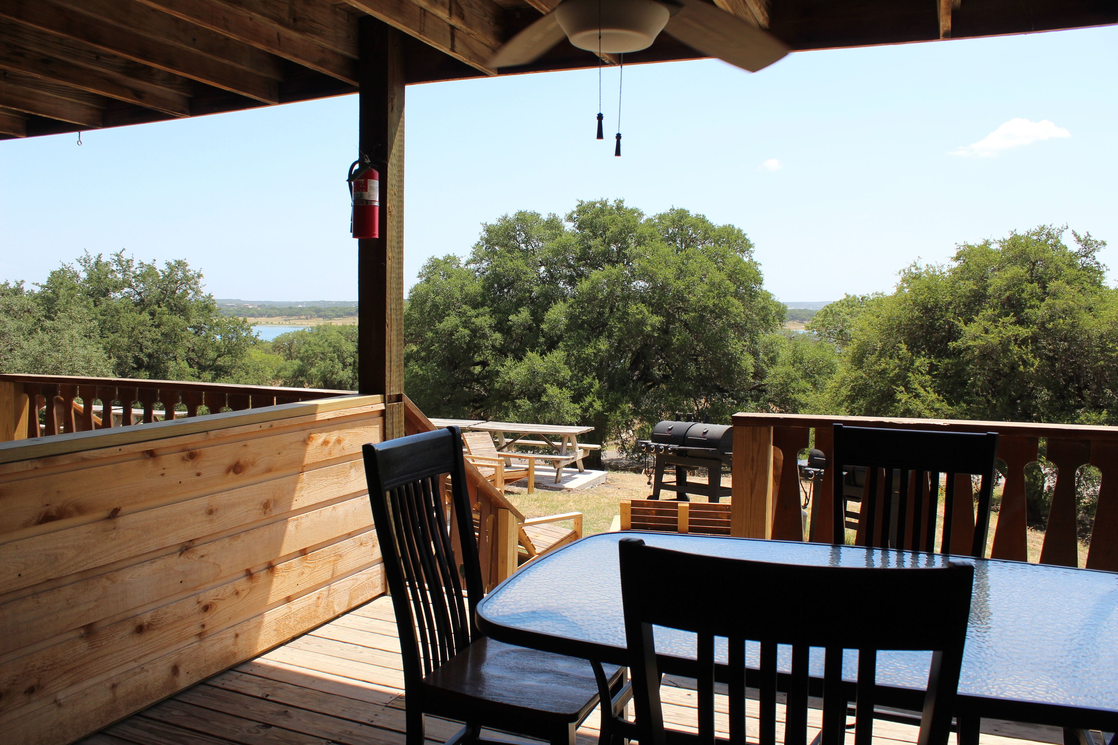 A wooden deck with a table and chairs, a barbecue grill, and a fire extinguisher.