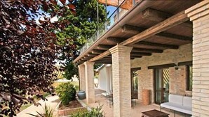 A covered patio area with a seating arrangement, a potted plant, and a view of the surrounding greenery. - Casali Costadoro (Acquaviva Picena)